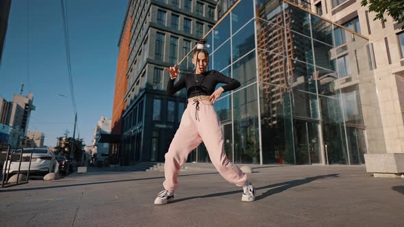 Young Woman Dances Hiphop Against Building on City Street