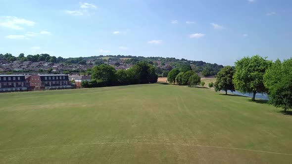 Aerial, drone launching from field revealing Exeter cityscape in UK on sunny day