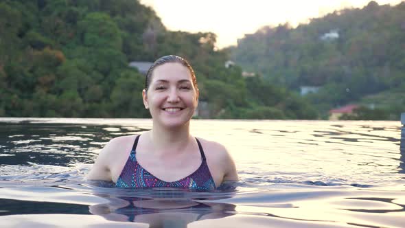 Smiling Lady in Coloured Swimsuit Approaches in Blue Pool