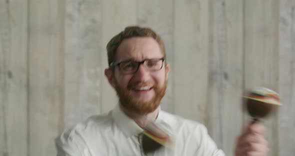 Happy Bearded Man with Glasses and a White Shirt Dancing with Maracas