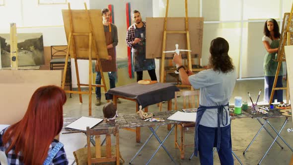 Teacher holding figurine while interacting with artist