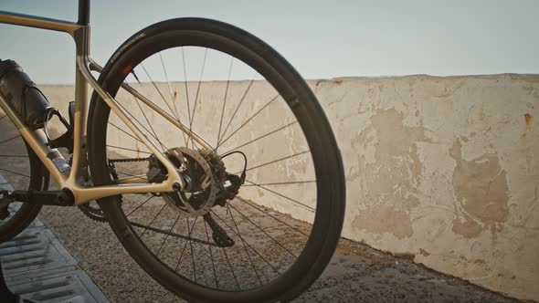 Unknown Female in Cycling Shoes and Sportswear is Coming to Concrete Parapet Taking Her Bicycle