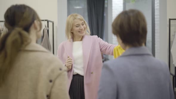 Positive Happy Woman Showing Yellow Blouse To Friends in Shopping Mall and Leaving To Dressing Room