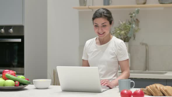 Young Indian Woman Doing Video Call on Laptop in Kitchen