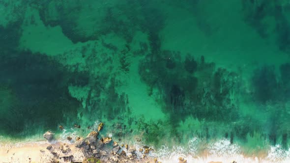 Aerial View of Green Transparent Sea Waves Quietly Splashing on Rocky Beach