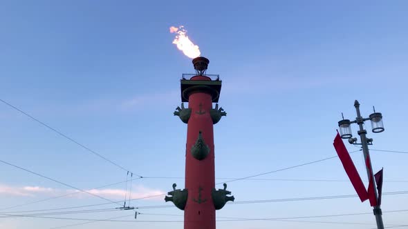 A fire burns on the top of the rostral column. Flame at the blue sky background