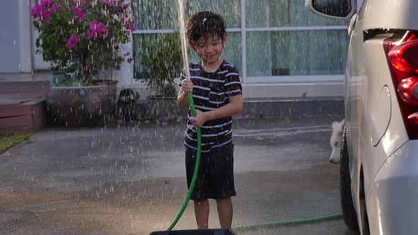 Cute Asian Boy Has Fun Playing In Water From A Hose Outdoors Slow Motion