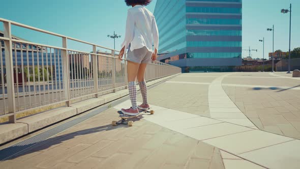 Beautiful young woman cruising around the city with her longboard.
