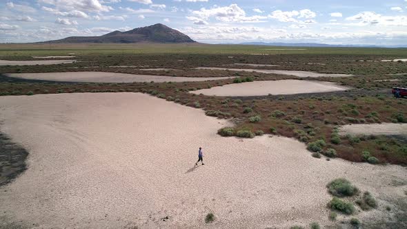 Lone person walking through the desert over cracked terrain