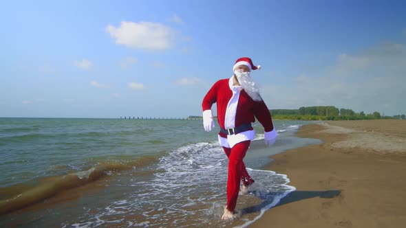 Santa Claus in costume walks along sandy shore of sea