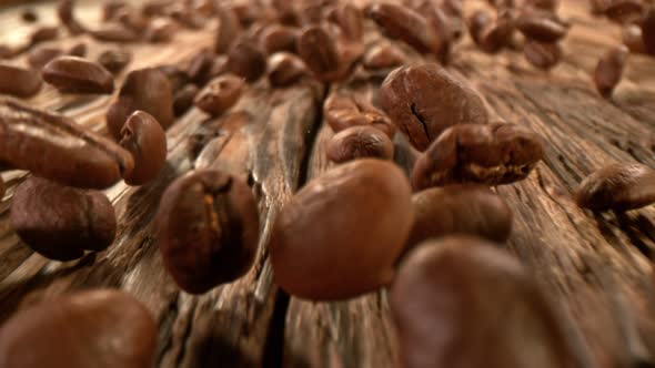 Super Slow Motion Detail Shot of Coffee Beans Strewing on Wooden Background at 1000Fps with Motion