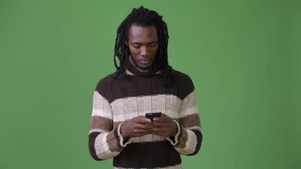 Young Handsome African Man with Dreadlocks Against Green Background