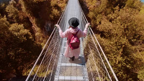 Woman Walks on Footbridge Over Gorge Among Yellowed Trees