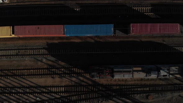 Aerial View of a Large Train on the Rails Next To the River. The Camera Flies Over a Long Train of