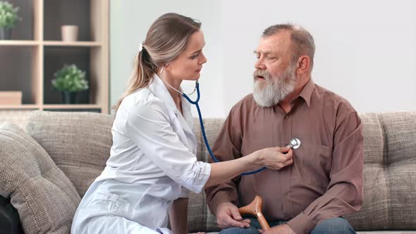 Female Doctor Listening Breathing Heartbeat of Elderly Disabled Man Patient Stethoscope on Chest