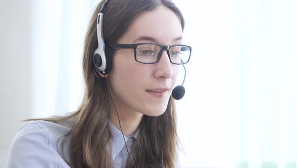 Young Woman Wearing Headphones Communicating Online Via Laptop Explaining Teaching