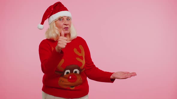 Grandmother in Christmas Deer Sweater Showing Thumbs Up and Pointing at on Blank Advertisement Space