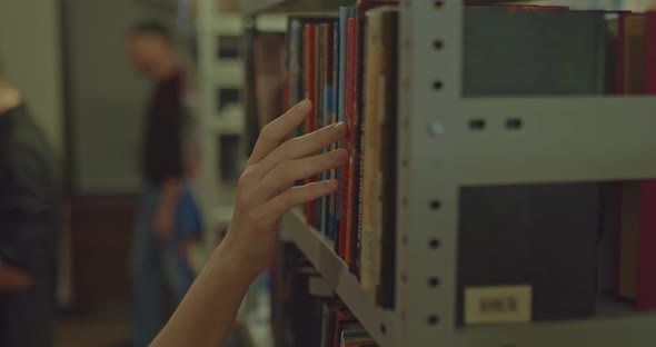 Closeup a Woman's Hand Runs Through the Books