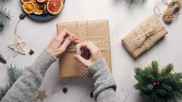 Female Hands Tie a Bow on Box with Christmas Gift