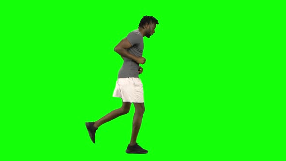 African American Man Is Running at Green Screen, Chroma Key. Profile View.