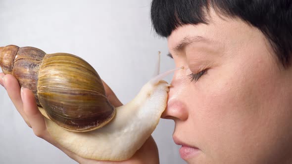 Pretty woman with big african snail on her face