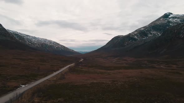 Drone flight along valley between mountains dusted with snow, Northern Norway