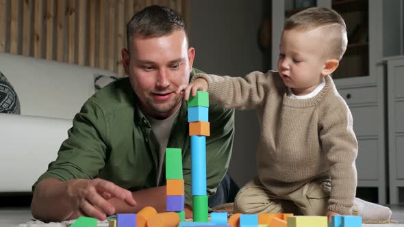 Father and Son Build Tower Using Colorful Wooden Blocks