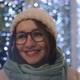 A beautiful smiling brunette in glasses in a winter hat in the night city. - VideoHive Item for Sale