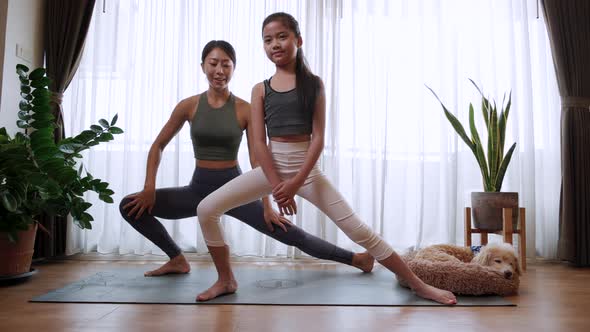 Happy and Healthy mom and little girl doing practicing yoga together on yoga mat at home