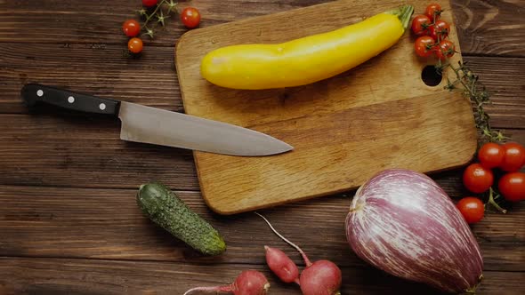 Yellow eggplant on a wooden board while preparing healthy food with vegetables, top down shot