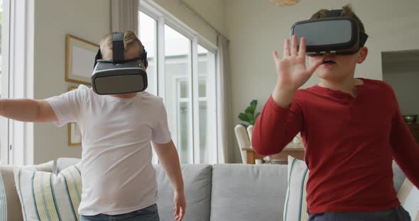 Caucasian boy with brother using vr headsets and standing in living room