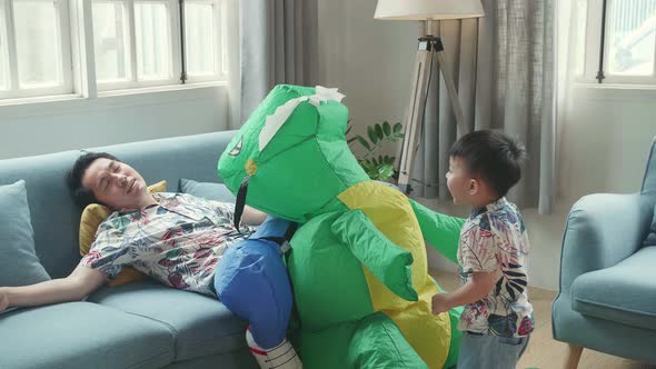 Tried Asian Father After Play With His Son,  Funny Boy Kick Dinosaur Toy In Modern House Living Room