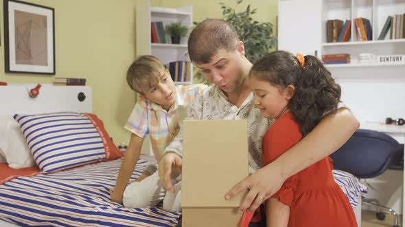 Children giving gift box to their father. alt