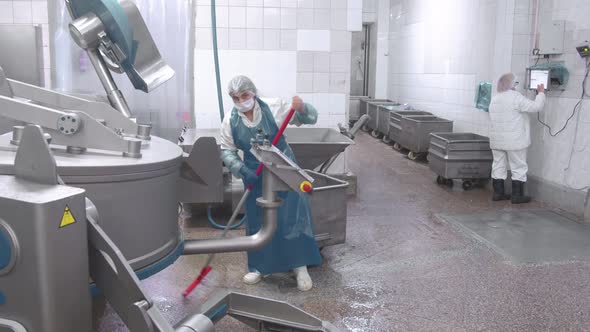 Worker Washes the Equipment with Water From a Hose at the Enterprise. Sanitary Cleaning of Sausage