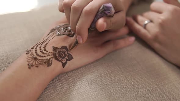 Artist Is Drawing Mehendi Pattern on Hands, Applying Paste From Tube, Close-up