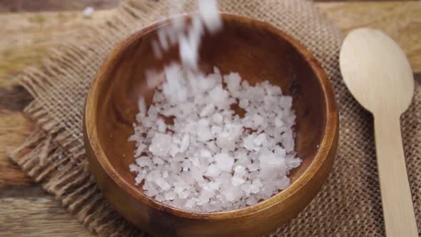 Sea mineral coarse rough salt. Falling into a wooden rustic bowl