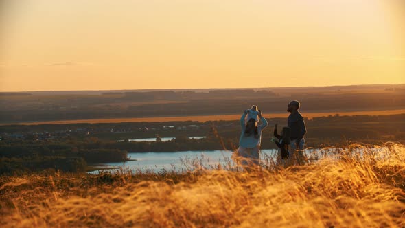 Young Family Playing with Kite in Nature While the Sunset