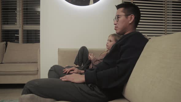 Father watching TV with his daughter