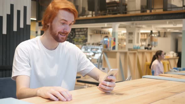 Video Chat on Smartphone by Redhead Beard Man in Cafe