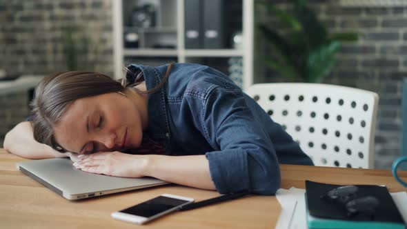 Exhausted Young Lady Sleeping on Laptop at Work Resting After Hard Day