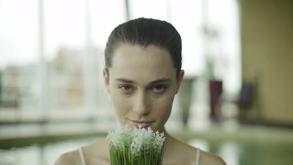 Young woman smelling flowers and smiling cheerfully, portrait