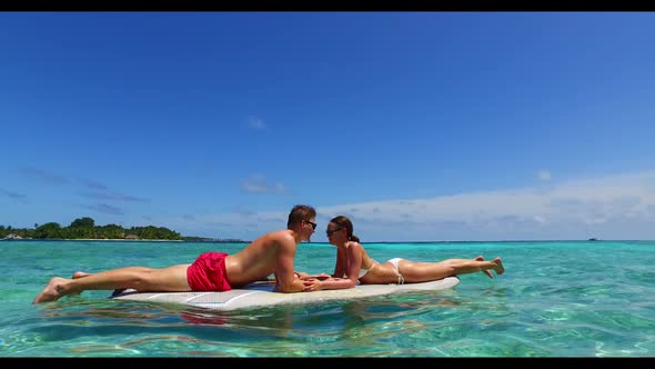 Two people posing on beautiful shore beach trip by clear lagoon and white sand background of the Mal