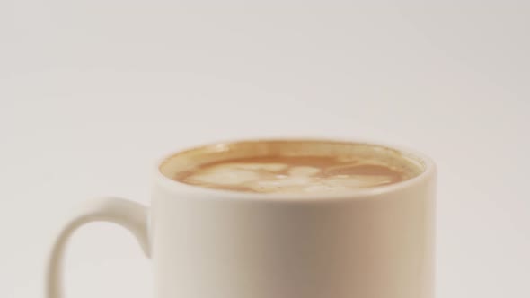 Warm milk drops falling into cup of fresh cappuccino