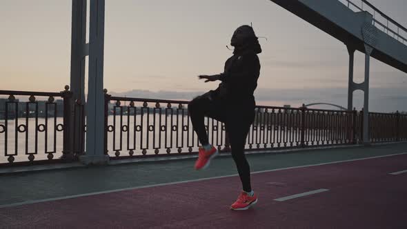 Sporty African American Guy Warming Up and Start Run Workout on City Bridge Training in Evening