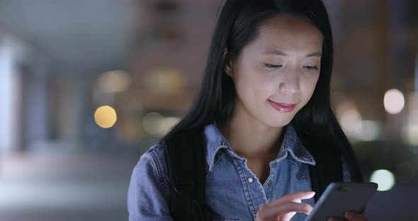 Woman watching on mobile phone in city at night