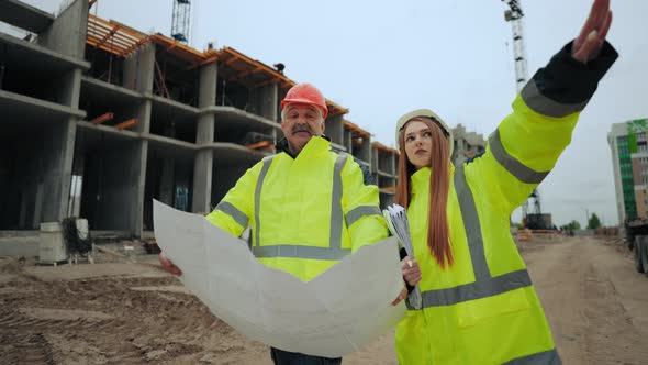 Female Construction Engineer and Aged Professional Foreman are Discussing Construction Plan in alt