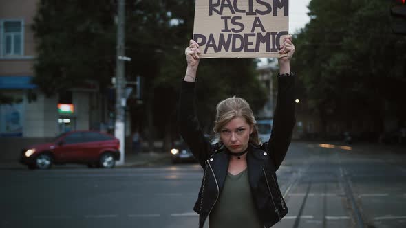 Woman Hipster is Raising Up Cardboard Poster Inscription Racism is a Pandemic