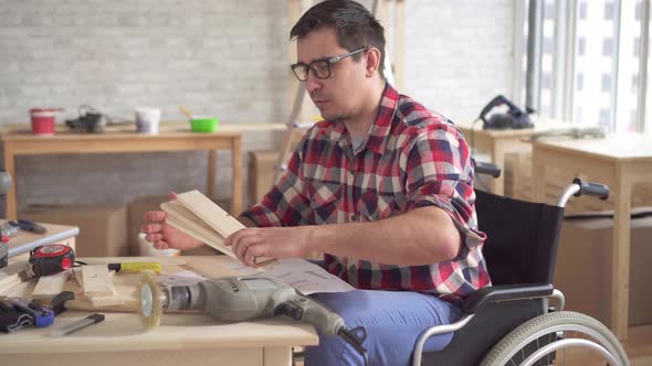 Portrait of a Young Disabled Person in a Wheelchair with an Electric Drill Engaged in the Assembly