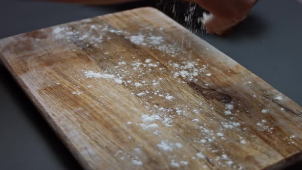 Pouring Flour on a Wooden Tray to Mold the Dough for Tuna Pizza