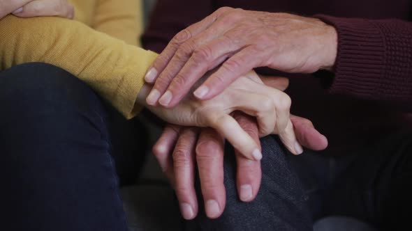 Mid section of senior caucasian couple sitting and holding hands